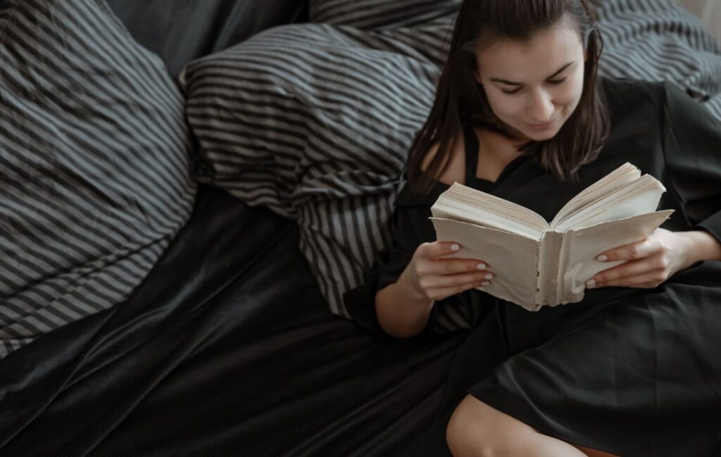 Mulher jovem lê um livro na cama