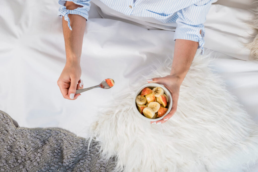 Pessoa comendo salada de frutas na cama