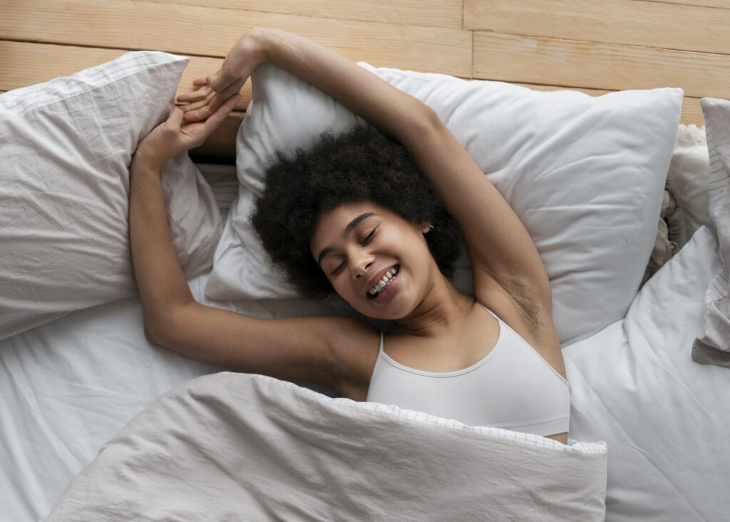 mulher negra dormindo feliz tirando um cochilo deitada sobre o travesseiro na cama para recuperar o sono perdido