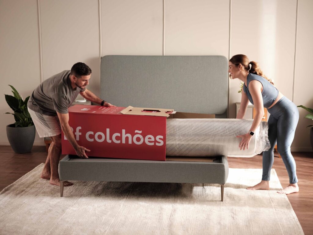 casal homem e mulher colocando colchão a vácuo no box sobre a cama box e desembalando
