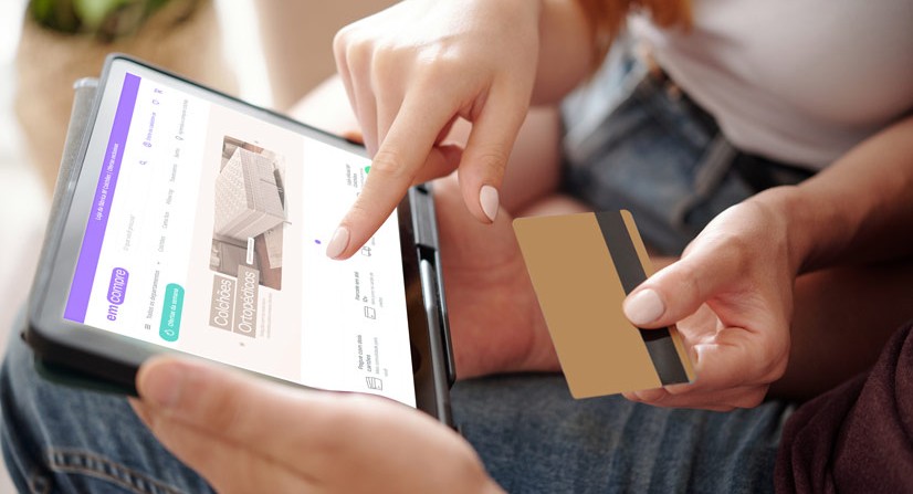 pessoas com uma tablet ipad  e cartão de crédito na mão comprando colchão online no site Emcompre